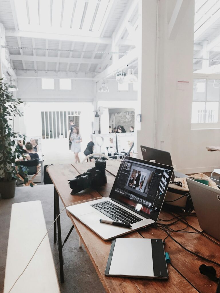 Home A bright, modern workspace featuring laptops, a camera, and a drawing tablet in an indoor office.